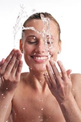 Frau spritzt sich Wasser ins Gesichts